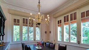 Una sala menjador amb un penjoll, grans finestres i una taula amb cadires.