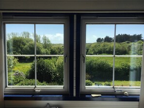 Ein Zimmer mit zwei Fenstern mit Blick auf eine grüne Landschaft.