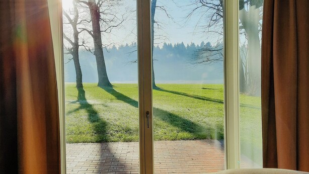 A room with a large sliding glass door leading to an outdoor area with a grassy lawn and trees. - Forestry chic: flat with lake and forest view (Friedeburg)
