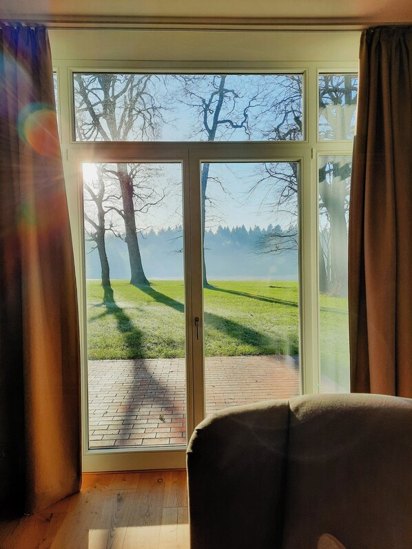 A room with a large sliding glass door leading to an outdoor area with a grassy lawn and trees. - Forestry chic: flat with lake and forest view (Friedeburg)