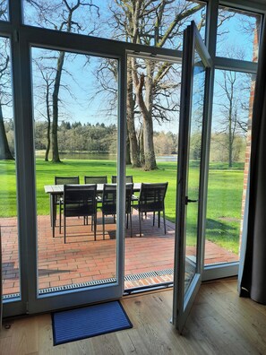 A room with a sliding glass door leading to an outdoor patio with a table and chairs. - Forestry chic: flat with lake and forest view (Friedeburg)