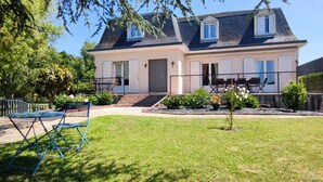 Uma casa de dois andares com varanda, porta da frente e um pequeno jardim.
