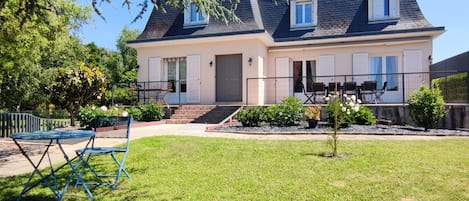Een tweelaags huis met een balkon, een voordeur en een kleine tuin.