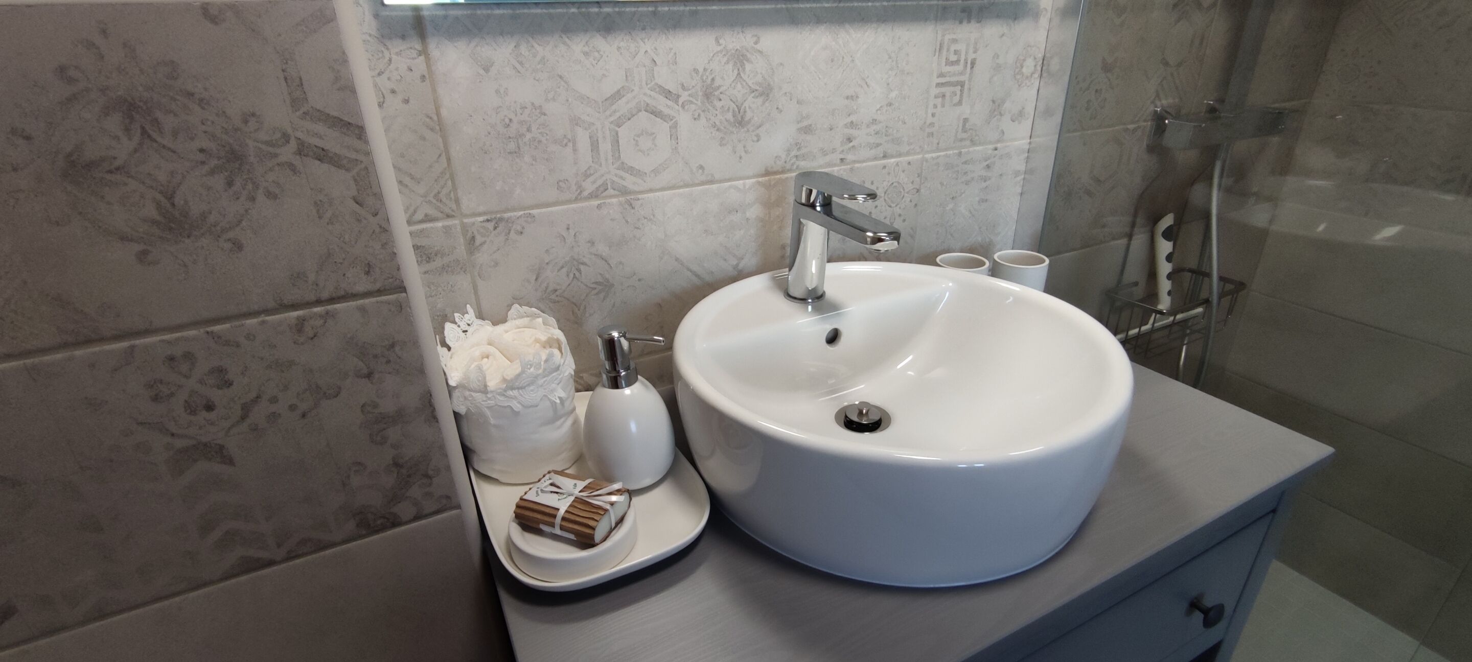 Une salle de bain avec un lavabo blanc, un miroir et un espace douche.