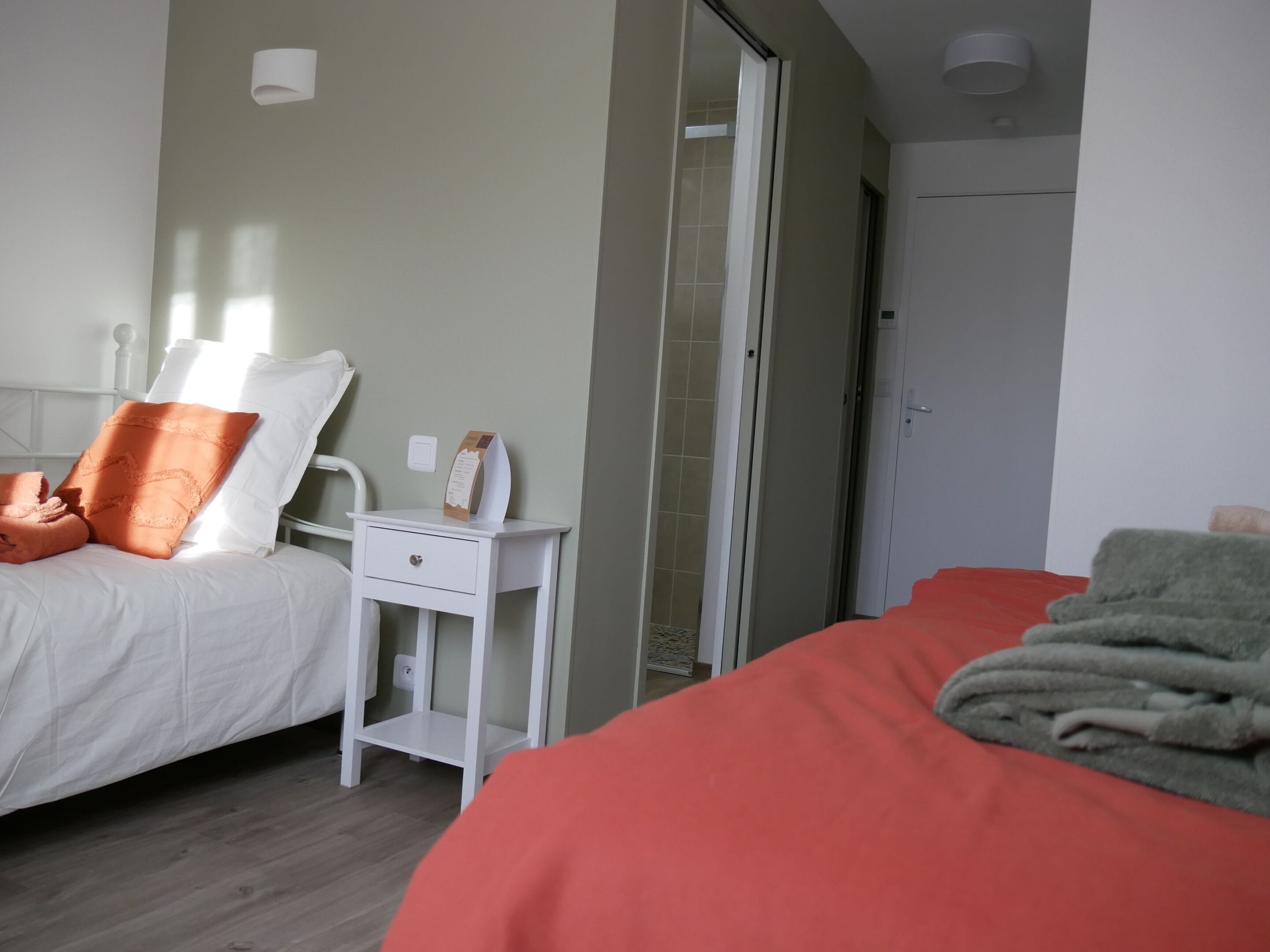 Une chambre d’hôtel avec un lit, une table de chevet, un miroir et une porte.