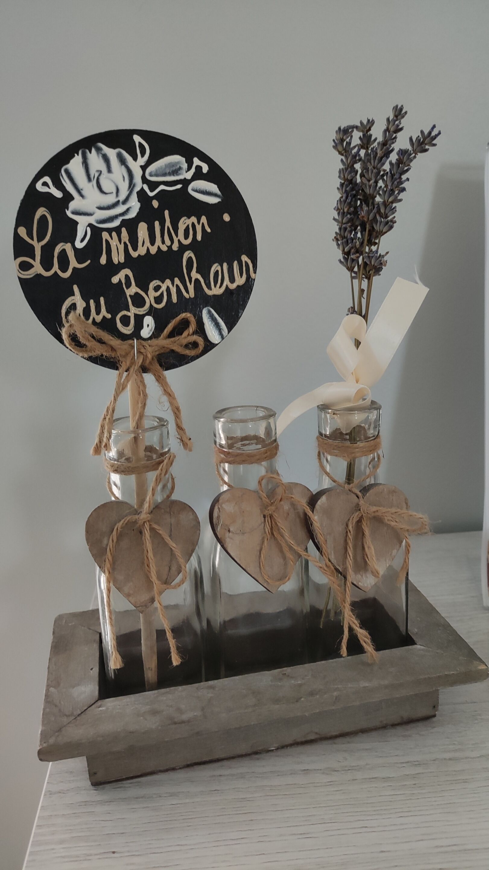 A decorative arrangement with a sign, jars, and dried flowers.