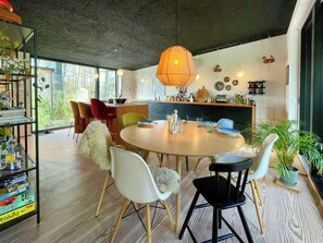 A modern dining area with a round table, chairs, and a hanging light fixture. - Holiday home with forest view 200 m from beach (Tved)