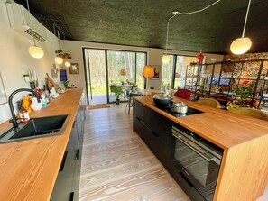 A modern kitchen with a wooden countertop, built-in oven, and a large window. - Holiday home with forest view 200 m from beach (Tved)