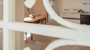A modern kitchen with white cabinets, a dining area with a wooden table, and a decorative white metal gate. - Historic residence with garden in Salento (Nardo')