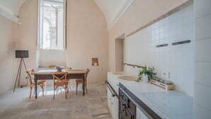 A kitchen with a dining table, chairs, a large window, and a sink. - Historic residence with garden in Salento (Nardo')