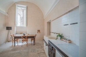 Eine Küche mit Esstisch, Stühlen, einem großen Fenster und einer Spüle.