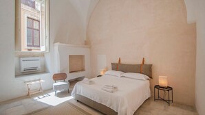 A bedroom with a bed, a chair, a bedside table, a lamp, and a window. - Historic residence with garden in Salento (Nardo')