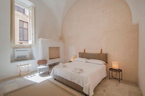 Ein Schlafzimmer mit Bett, Stuhl, Nachttisch, Lampe und Fenster.