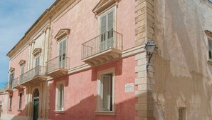 A pink building with a balcony, a door, and a lamp post. - Historic residence with garden in Salento (Nardo')