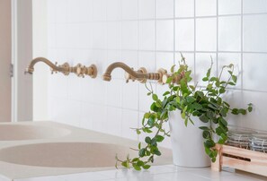 Ein Badezimmer mit einer Badewanne, einer weißen Fliesenwand und einem Blumentopf.