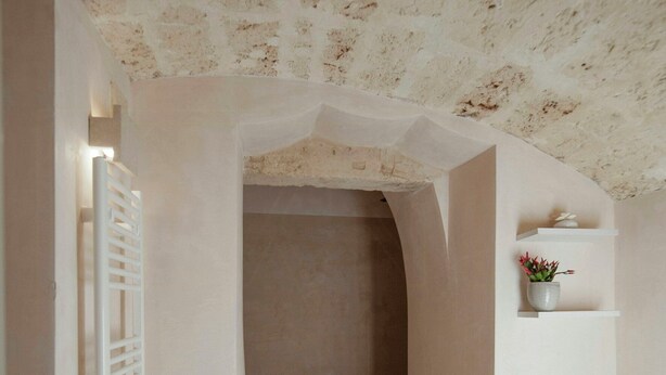 A bathroom with a stone ceiling, a white radiator, a shower area, and a white bathtub. - Historic residence with garden in Salento (Nardo')