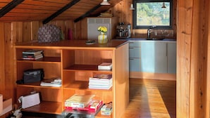 Een houten interieur met een keukenhoek, een boekenkast en een raam.
