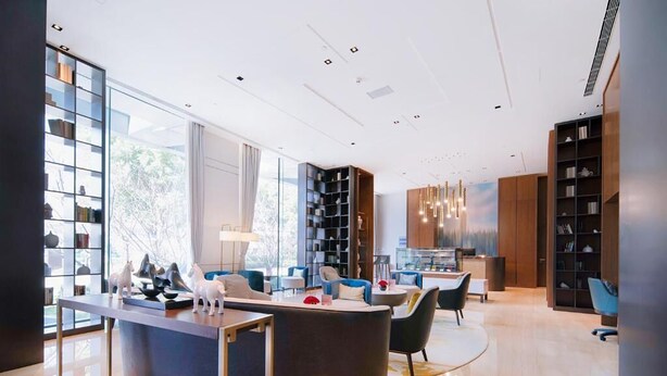 Un moderno vestíbulo de hotel con mostrador de recepción, zona de estar y estanterías.