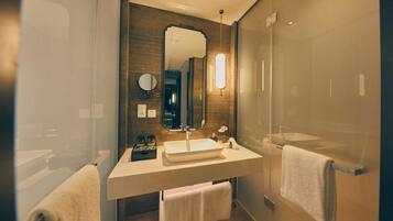 A modern bathroom with a large mirror, a sink, and a glass shower enclosure.