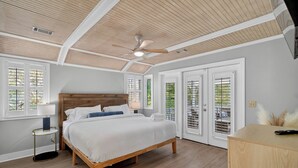 Ein Schlafzimmer mit einem hölzernen Bett, einem Deckenventilator und Blick durch das Fenster.