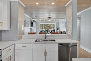 A modern kitchen with white cabinetry, a stainless steel dishwasher, and a built-in oven. - Shared Pool + Pickleball Court + Sunroom | Walk to the Beach | Isle Be There (Isle Of Palms)