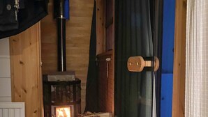 Una habitación de cabaña acogedora, con una cama, un hogar de leña y una puerta con picaporte de madera.