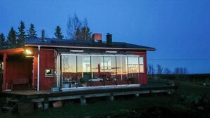 Una casa con un amplio ventanal, fachada roja y chimenea.