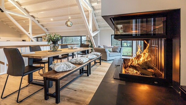 Un intérieur moderne avec une cheminée, des meubles en bois et un plafond haut.