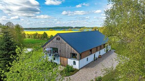 A rustic barn-style building with a blue roof, surrounded by lush greenery and fields. - Traditional architecture meets modern design (Thumby)