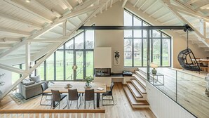Un loft spacieux avec de hauts plafonds, de grandes fenêtres et un coin repas offrant une vue sur l’extérieur.