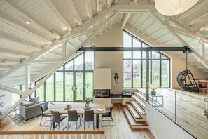 A spacious loft with high ceilings, large windows, and a dining area with a view of the outdoors. - Traditional architecture meets modern design (Thumby)