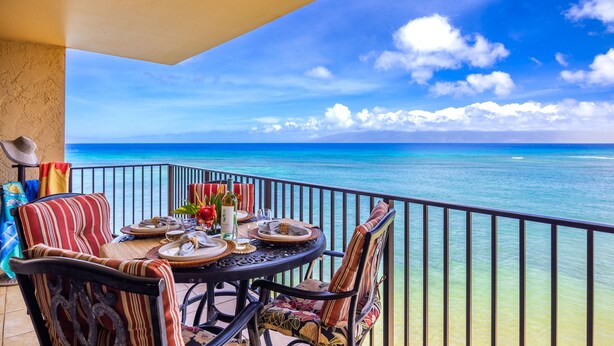 A balcony with a table set for dining, overlooking a clear blue sea. - Oceanfront Corner-Unit, Large Lanai, Amazing Sunsets, Views! (Lahaina)