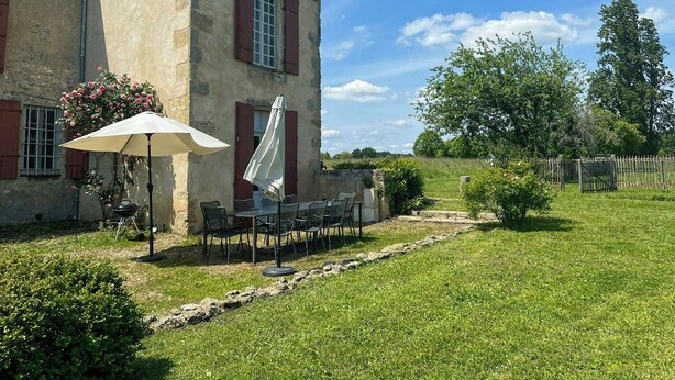 A rustic stone building with a patio area featuring outdoor seating and a table with a canopy. - 18th-century estate between Bordeaux and Sauternes (Saint-Côme)