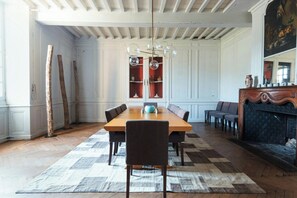Ein Esszimmer mit Holztisch, Stühlen, einer Chandelüster und einem Kamin.