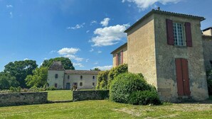 A rustic building with a stone wall, a small garden, and a clear blue sky. - 18th-century estate between Bordeaux and Sauternes (Saint-Côme)