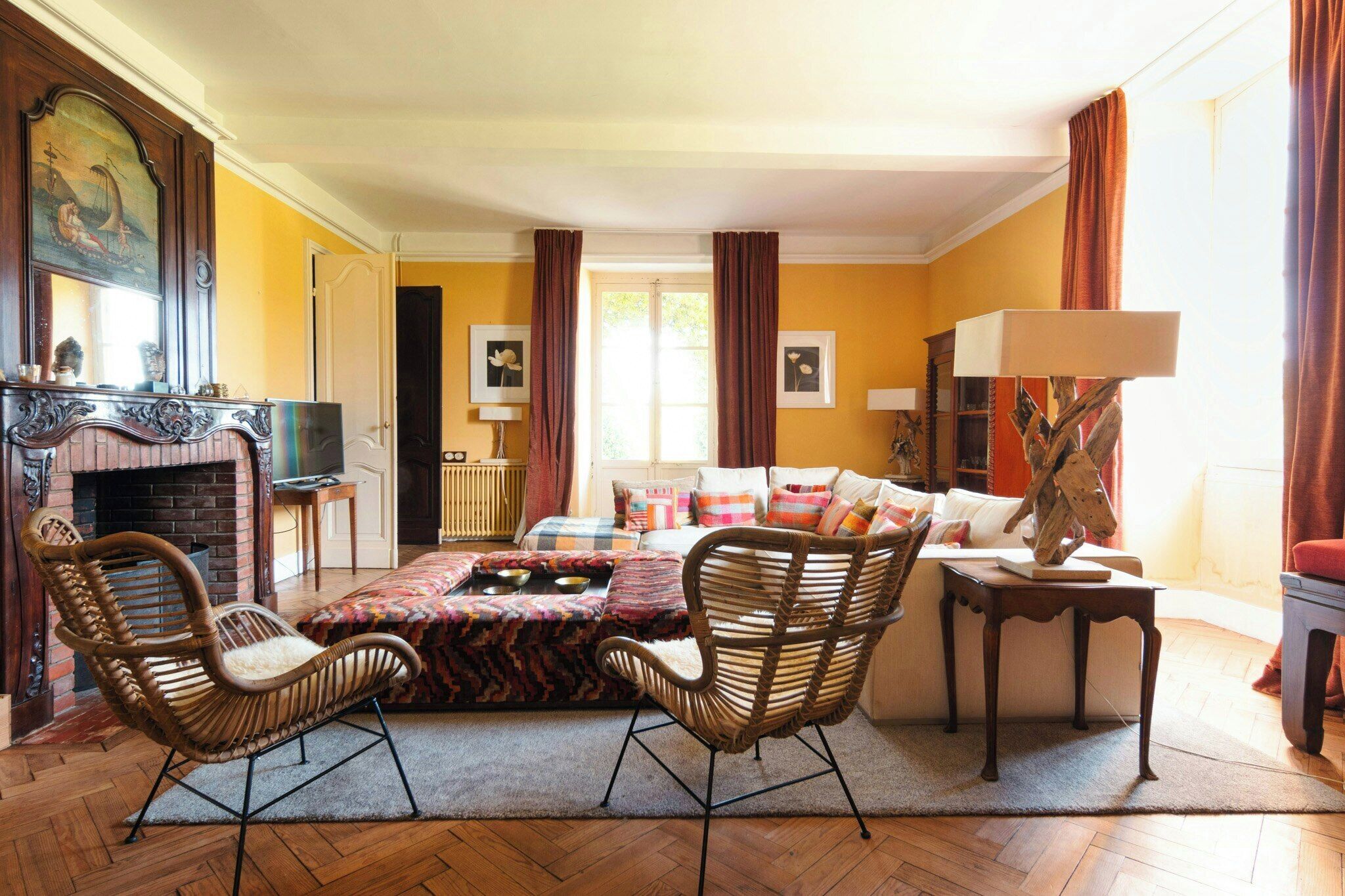 A living room with a fireplace, wicker chairs, a sofa, and a lamp.