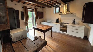 Une cuisine rustique avec des poutres en bois, des armoires blanches, une table à manger et un four encastré.