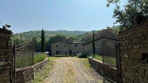Une allée de gravier mène à un bâtiment en pierre doté d’un portail en métal.