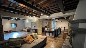 Un espace de vie à aire ouverte comprenant un canapé, une table à manger, un mur en pierre et une cheminée.