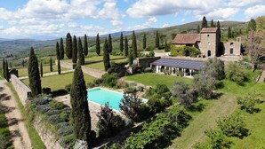 Une propriété située à la campagne, dotée d’une piscine, de murs en pierre et d’un grand bâtiment surmonté d’un toit en tuiles.