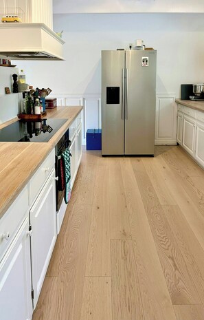 Eine moderne Küche mit weißen Schränken, einem Edelstahlkühlschrank und einer Holz Arbeitsplatte.