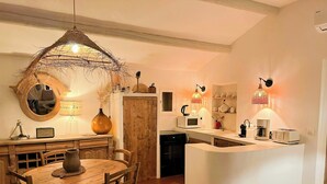 A kitchen with a wooden dining table, chairs, a central island, and pendant lighting. - Bohemian house overlooking Roussillon (ROUSSILLON)