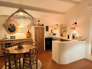 A kitchen with a wooden dining table, chairs, a central island, and pendant lighting. - Bohemian house overlooking Roussillon (ROUSSILLON)
