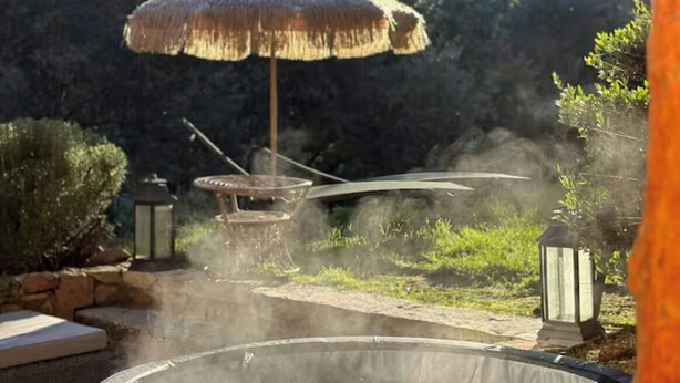 A hot tub with steam rising, surrounded by greenery and a thatched umbrella. - Bohemian house overlooking Roussillon (ROUSSILLON)