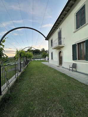 A building with a balcony, a paved pathway, and a grassy area. - Villa with pool in the Arezzo countryside (Arezzo)