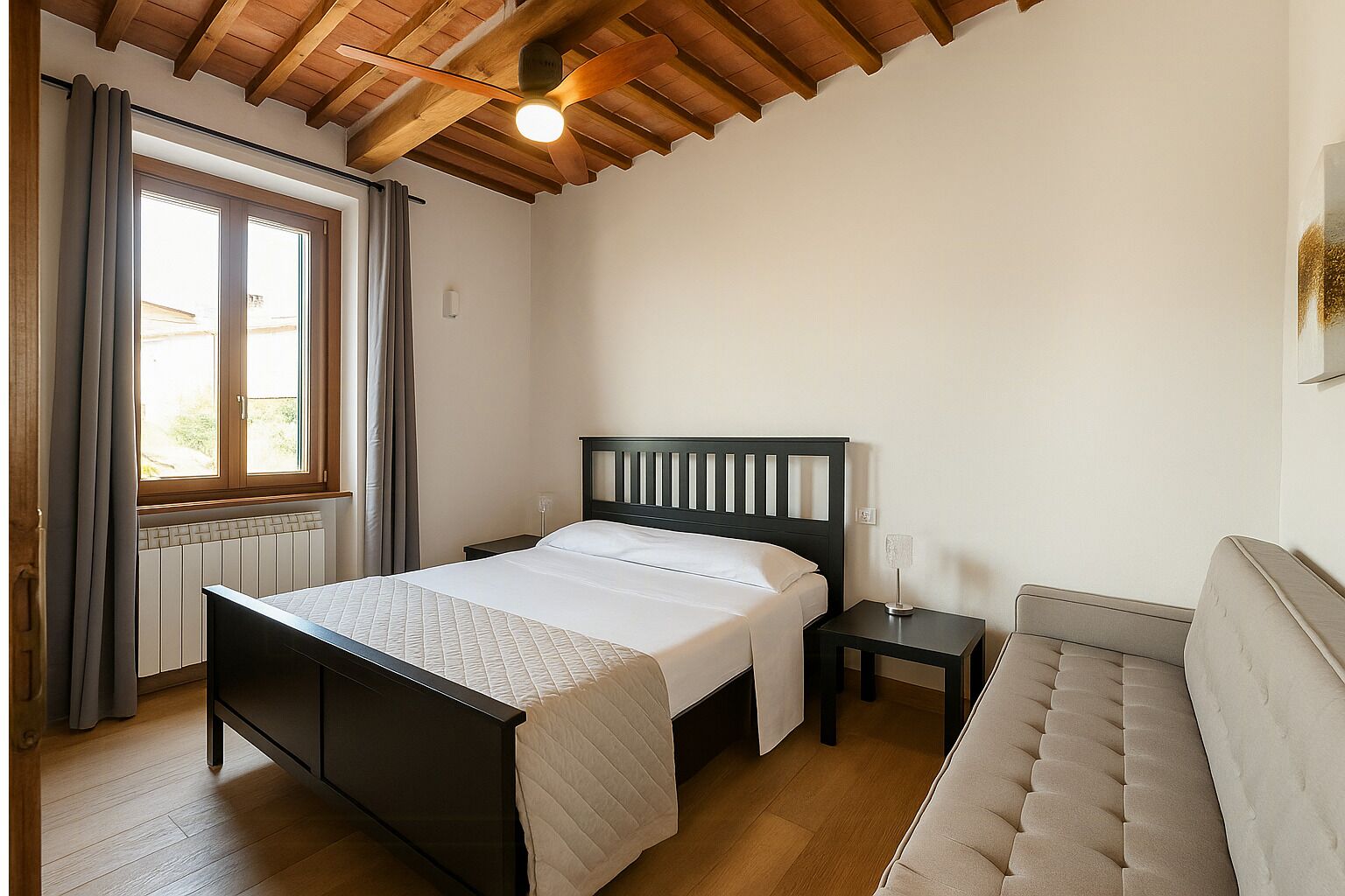 A bedroom with a bed, bedside table, and a sofa.