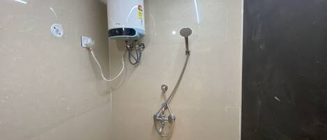 A shower with a wall-mounted heater, a handheld showerhead, and a visible electrical outlet.