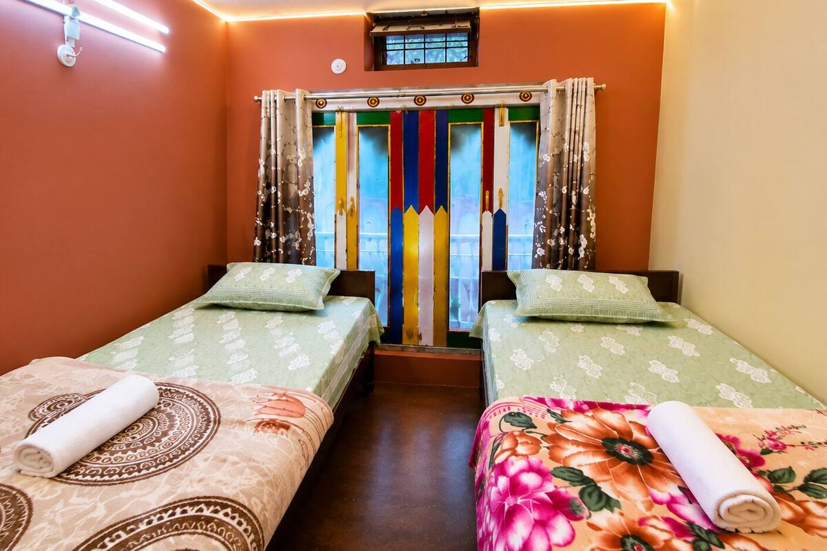 Une chambre avec deux lits, chacun recouvert d’une couvre-lit à motifs et agrémenté d’une serviette roulée.