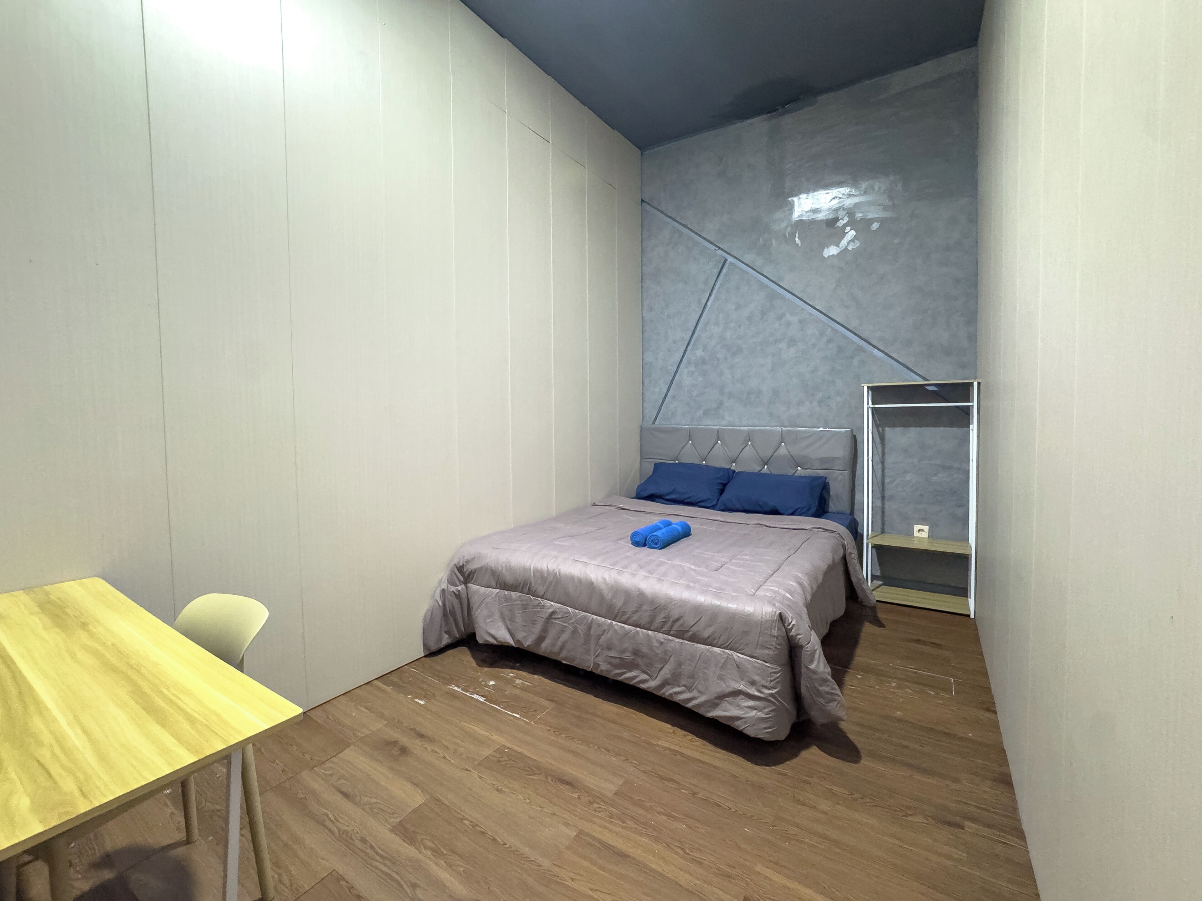 A bedroom with a bed, a wooden table, and a chair.