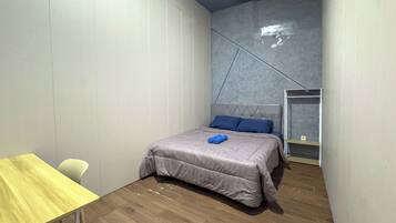 A bedroom with a bed, a wooden table, and a chair.